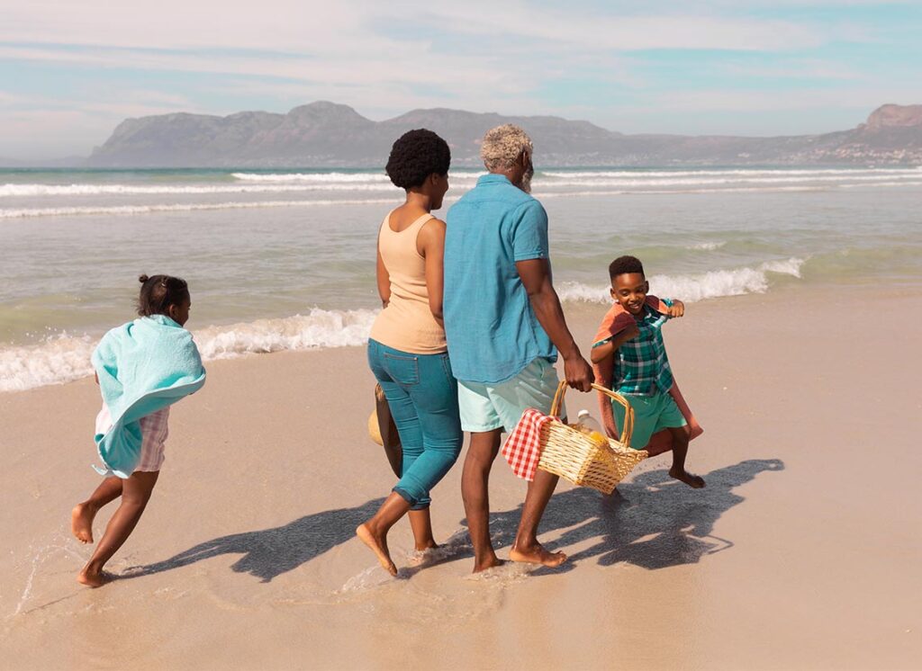 grandparents walking on the beach with their grandchildren carrying a picnic basket successful retirement strategies
