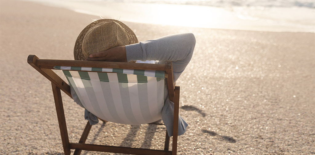 senior relaxing in beach chair facing the ocean how to save for retirement