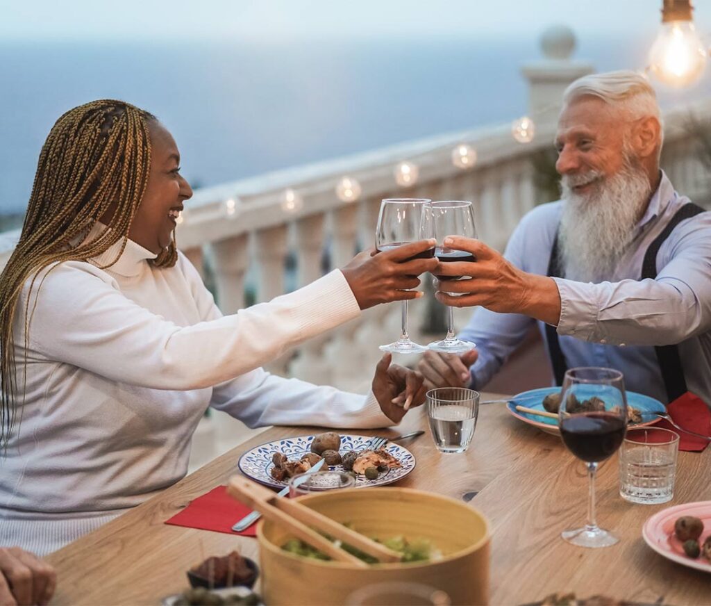 seniors having dinner on a balcony by the ocean successful retirement strategies